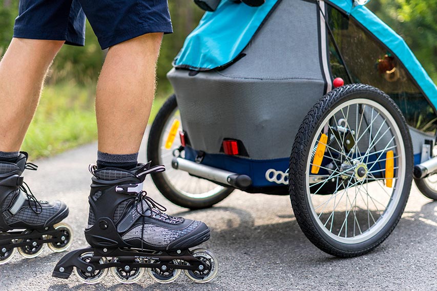 Un parent qui propulse une poussette à grandes roues en roller