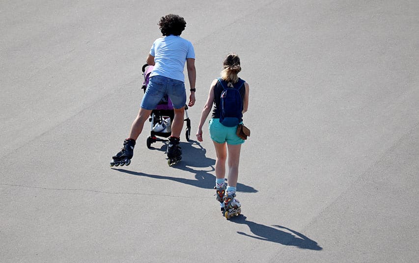 Un couple en roller avec sa poussette