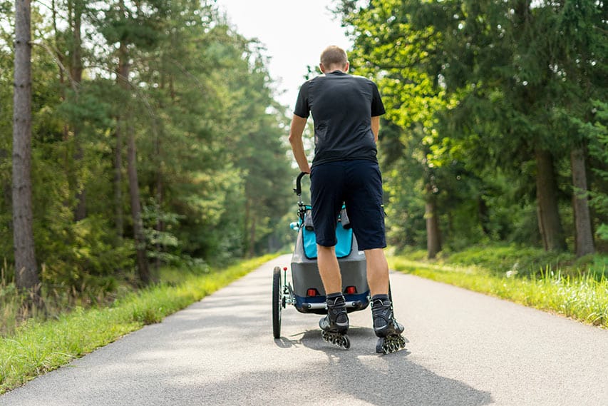 Un papa en roller propulse une poussette